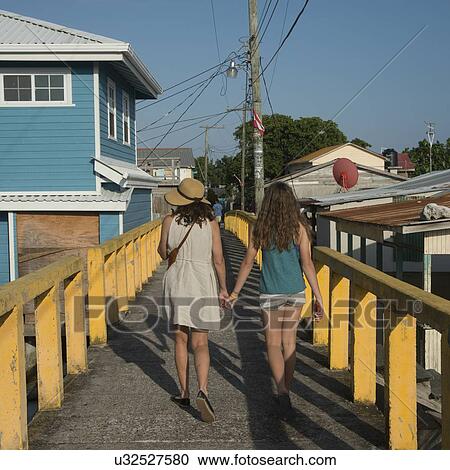Stock Image - Woman and her daughter walking on a bridge, Cayman Cay, Utila Island, Bay Islands, Honduras. Fotosearch