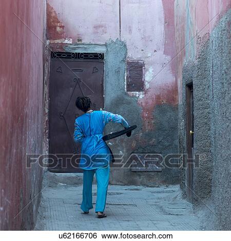 Stock Photograph - Woman carrying tray on a street, Medina, Marrakesh, Morocco. Fotosearch