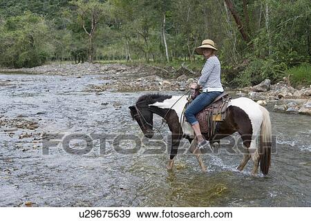 Woman crossing a river on a horse, Finca El Cisne, Honduras View Large Photo Image Stock Photo - Woman crossing a river on a horse, Finca El Cisne, Honduras. Fotosearch