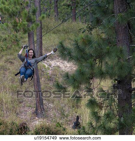 Stock Photo - Woman riding a zip line in a forest, Copan, Copan Ruinas, Copan Department, Honduras. Fotosearch