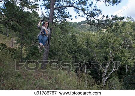 Stock Photo - Woman riding a zip line in a forest, Copan, Copan Ruinas, Copan Department, Honduras. Fotosearch
