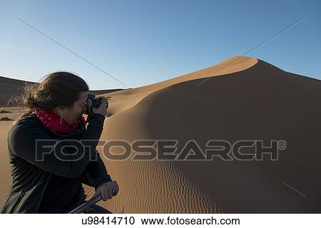 Stock Image - Woman taking picture of Erg Chegaga Dunes in Sahara Desert, Souss-Massa-Draa, Morocco. Fotosearch