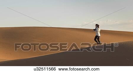 Stock Photograph - Woman walking on Erg Chegaga Dunes in Sahara Desert, Souss-Massa-Draa, Morocco. Fotosearch