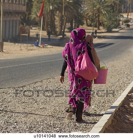 Stock Photo - Women walking on roadside, Morocco. Fotosearch