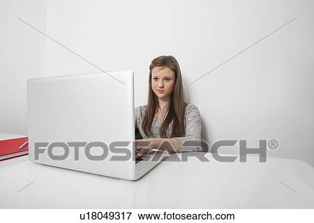 Stock Photo - Beautiful businesswoman working on laptop at office desk. Fotosearch