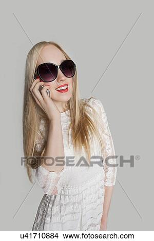 Beautiful girl answering cell phone against gray background View Large Photo Image Picture - Beautiful girl answering cell phone against gray background. Fotosearch