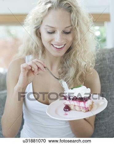 Stock Image - Beautiful woman having raspberry cake in house. Fotosearch