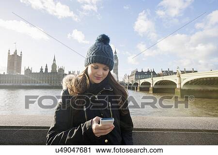 Beautiful young woman reading text message through smart phone by river Thames, London, UK View Large Photo Image Stock Image - Beautiful young woman reading text message through smart phone by river Thames, London, UK. Fotosearch