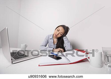 Stock Photograph - Bored businesswoman working at office desk. Fotosearch