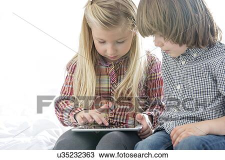 Brother and sister using tablet PC in bedroom View Large Photo Image Stock Image - Brother and sister using tablet PC in bedroom. Fotosearch