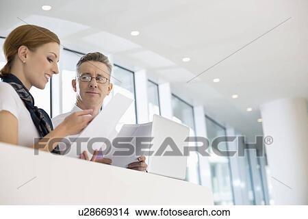 Business people discussing over documents in office View Large Photo Image Picture - Business people discussing over documents in office. Fotosearch