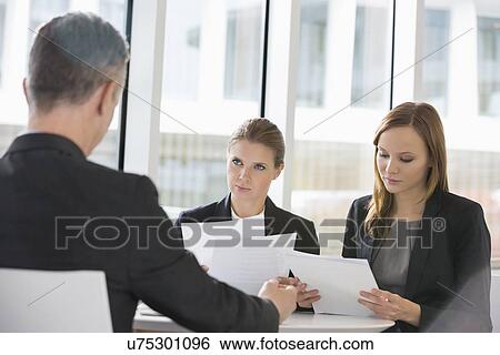 Business people discussing paperwork in office cafeteria View Large Photo Image Stock Photograph - Business people discussing paperwork in office cafeteria. Fotosearch