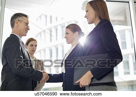 Stock Image - Business people shaking hands in office. Fotosearch