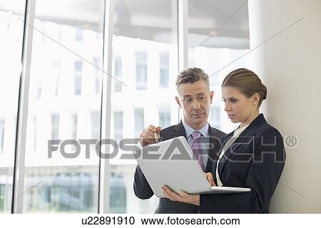 Stock Image - Business people using laptop in office. Fotosearch