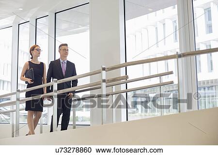 Business people walking by railing in office View Large Photo Image Stock Image - Business people walking by railing in office. Fotosearch