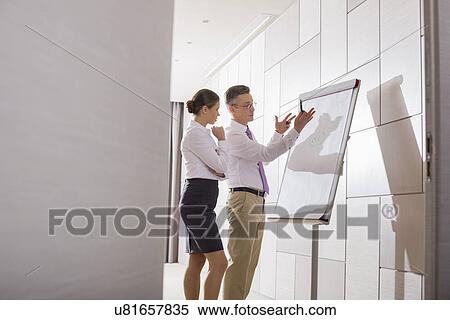 Stock Photography - Businessman explaining strategy to coworker in office. Fotosearch
