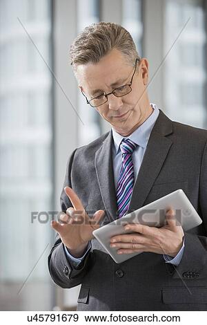 Stock Photo - Businessman gesturing while using digital tablet in office. Fotosearch