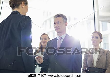 Businessman giving his card to female coworker in office View Large Photo Image Stock Photo - Businessman giving his card to female coworker in office. Fotosearch