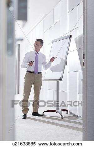 Businessman preparing for presentation on flipchart in office View Large Photo Image Stock Photography - Businessman preparing for presentation on flipchart in office. Fotosearch