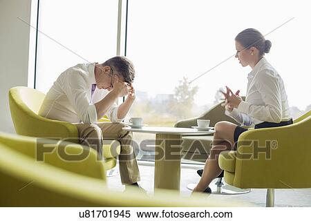 Stock Photography - Businesspeople in serious discussion at office lobby. Fotosearch