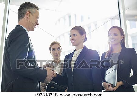 Stock Photo - Businesswoman giving her card to businessman in office. Fotosearch