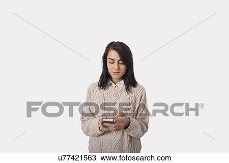 Businesswoman text messaging through smart phone against gray background View Large Photo Image Stock Image - Businesswoman text messaging through smart phone against gray background. Fotosearch