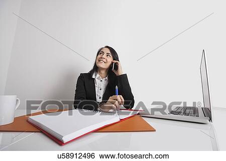 Businesswoman using cell phone at office desk View Large Photo Image Stock Photograph - Businesswoman using cell phone at office desk. Fotosearch