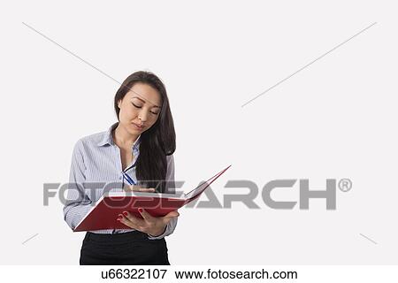 Businesswoman writing in book against gray background View Large Photo Image Stock Photo - Businesswoman writing in book against gray background. Fotosearch