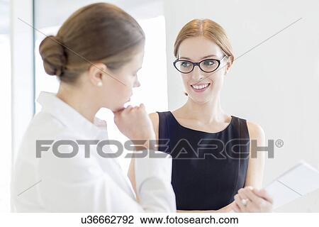 Stock Image - Businesswomen discussing in office. Fotosearch