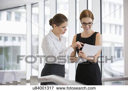 Businesswomen discussing over documents in office View Large Photo Image Stock Photo - Businesswomen discussing over documents in office. Fotosearch