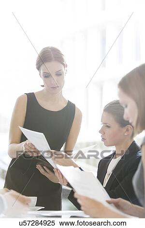 Stock Photography - Businesswomen doing paperwork during coffee break. Fotosearch