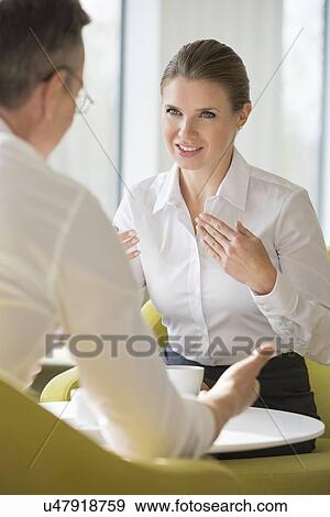 Businesswomen explaining to male colleague at office lobby View Large Photo Image Stock Photo - Businesswomen explaining to male colleague at office lobby. Fotosearch