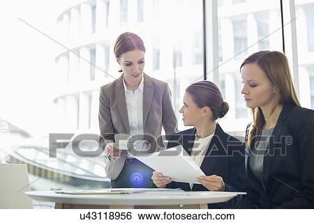 Businesswomen with paperwork during coffee break View Large Photo Image Stock Photograph - Businesswomen with paperwork during coffee break. Fotosearch