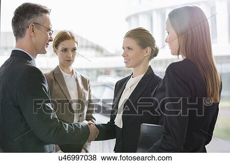 Confident business people shaking hands at workplace View Large Photo Image Stock Photo - Confident business people shaking hands at workplace. Fotosearch
