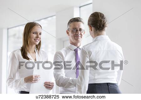 Stock Photography - Confident business people shaking hands in office. Fotosearch