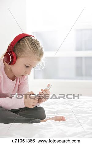 Cute girl listening music on smart phone in bedroom View Large Photo Image Stock Photograph - Cute girl listening music on smart phone in bedroom. Fotosearch