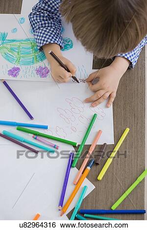 Stock Photograph - Directly above shot of boy drawing at home. Fotosearch