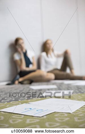 Documents on floor with tired businesswomen sitting in background View Large Photo Image Stock Photo - Documents on floor with tired businesswomen sitting in background. Fotosearch