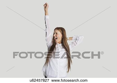 Stock Photo - Excited woman with arm raised screaming against white background. Fotosearch