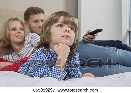 Stock Photo - Family watching TV in bedroom. Fotosearch