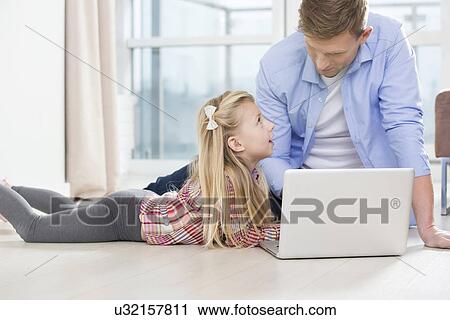 Father and daughter using laptop on floor in living room View Large Photo Image Stock Image - Father and daughter using laptop on floor in living room. Fotosearch