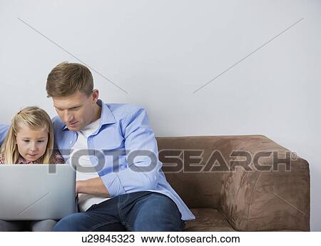Father and daughter using laptop together on sofa at home View Large Photo Image Stock Image - Father and daughter using laptop together on sofa at home. Fotosearch