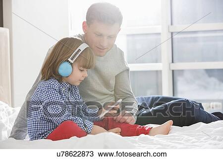 Father with boy listening music on headphones in bedroom View Large Photo Image Stock Image - Father with boy listening music on headphones in bedroom. Fotosearch