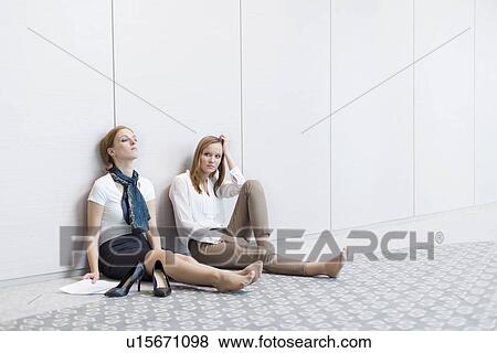 Frustrated businesswomen sitting on floor in office View Large Photo Image Stock Photo - Frustrated businesswomen sitting on floor in office. Fotosearch