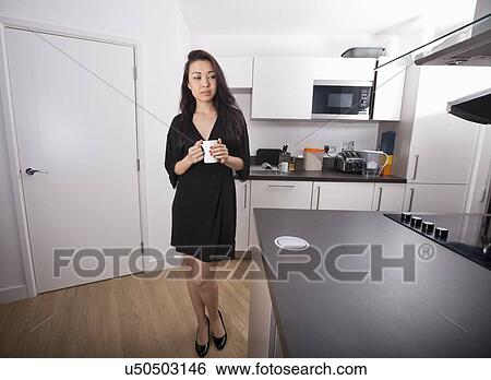 Full length of thoughtful young holding coffee mug in kitchen View Large Photo Image Stock Photograph - Full length of thoughtful young holding coffee mug in kitchen. Fotosearch
