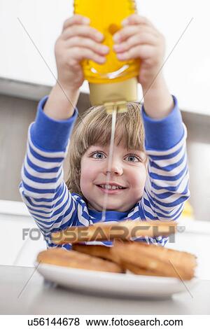 Happy boy pouring honey on waffles at home View Large Photo Image Stock Photo - Happy boy pouring honey on waffles at home. Fotosearch