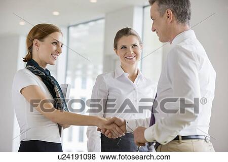 Stock Photo - Happy business partners shaking hands in office. Fotosearch