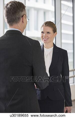 Happy businesswoman shaking hands with businessman in office View Large Photo Image Stock Photography - Happy businesswoman shaking hands with businessman in office. Fotosearch