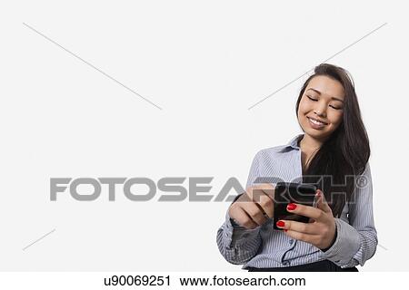 Happy businesswoman text messaging through smart phone against gray background View Large Photo Image Stock Image - Happy businesswoman text messaging through smart phone against gray background. Fotosearch