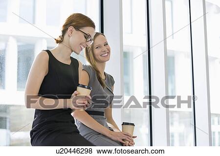 Happy businesswomen with disposable coffee cups at office View Large Photo Image Stock Photo - Happy businesswomen with disposable coffee cups at office. Fotosearch